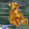 泰迪熊坐在公園椅子上淋雨
